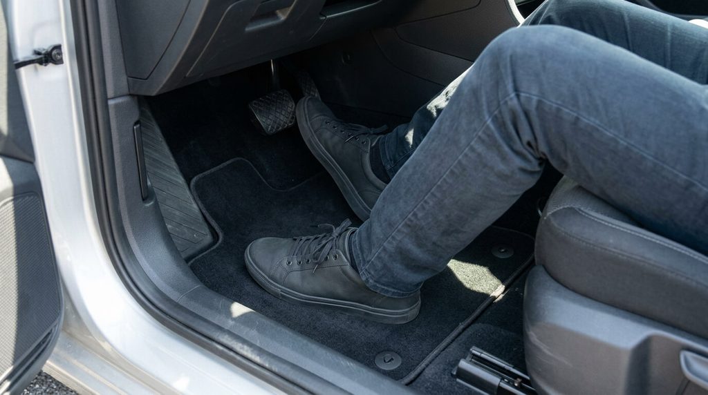 Secure driving footwear beside unobstructed pedals in a parked car.